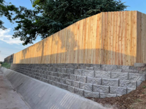 A completed wood fence installation on a stone retaining wall by DWM FENCE in Norman, OK