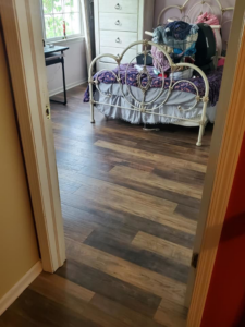 A bedroom with newly installed wood-look flooring, showcasing a completed job by TJS Floorcovering in Pennsauken, NJ.