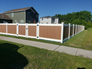 Newly installed composite privacy fence with brown panels and white posts by Wildfire Products Inc. in West Fargo, ND