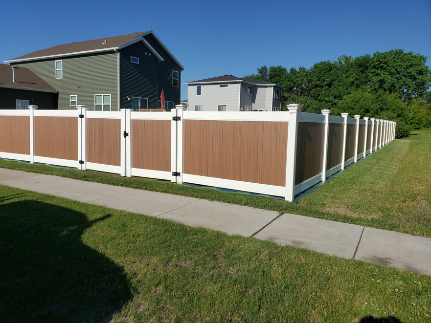 Newly installed composite privacy fence with brown panels and white posts by Wildfire Products Inc. in West Fargo, ND