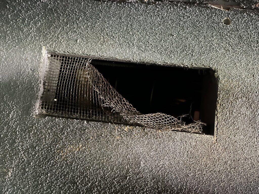 A compromised wall vent with damaged wire mesh, a potential pest entry point, identified by Ark Pest Management in Anaheim, CA.