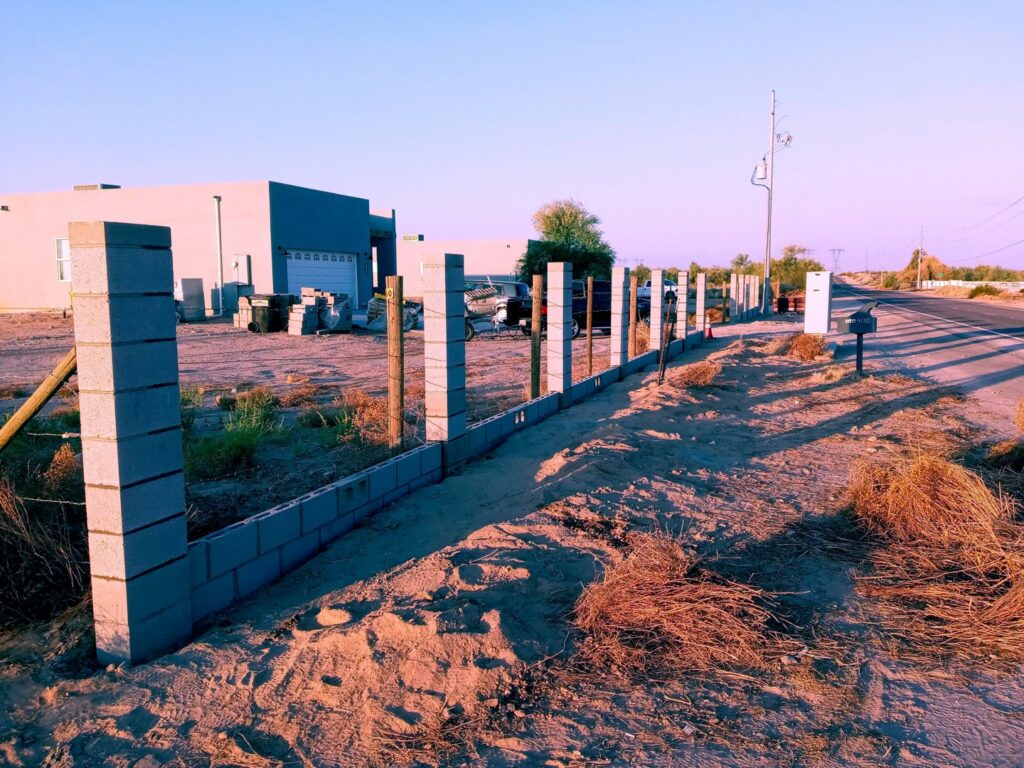 A concrete block fence under construction along a roadside by Arce Masonry LLC in Glendale, AZ