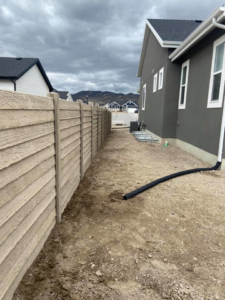 A durable concrete fence running alongside a new home, expertly installed by BroKrete Fencing LLC in Salt Lake City, UT