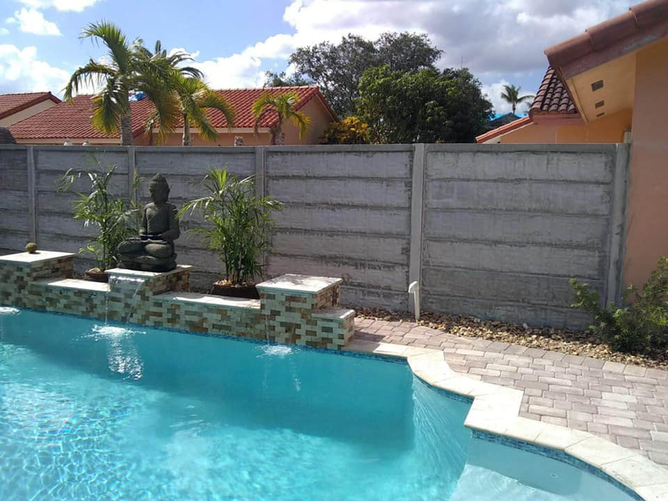 A concrete panel fence installed behind a swimming pool by Miami Concrete Fence in Miami, FL