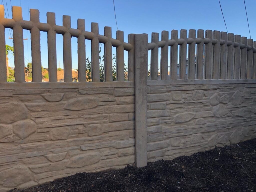 A concrete fence featuring a stone texture base and vertical pickets on top by StackWall Manufacturing in Pomona, CA.