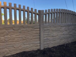 A concrete fence featuring a stone texture base and vertical pickets on top by StackWall Manufacturing in Pomona, CA.