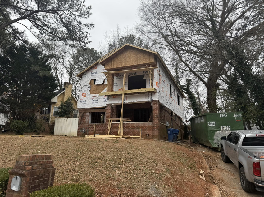 A large green dumpster for construction debris removal at a house under renovation by Helping Hand HVAC & Maintenance in Atlanta, GA.