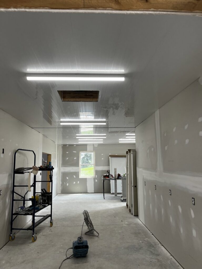 Fluorescent strip lights installed on the ceiling of a room during the construction phase, a service provided by Superior Electrical Solutions llc in Clear Spring, MD.