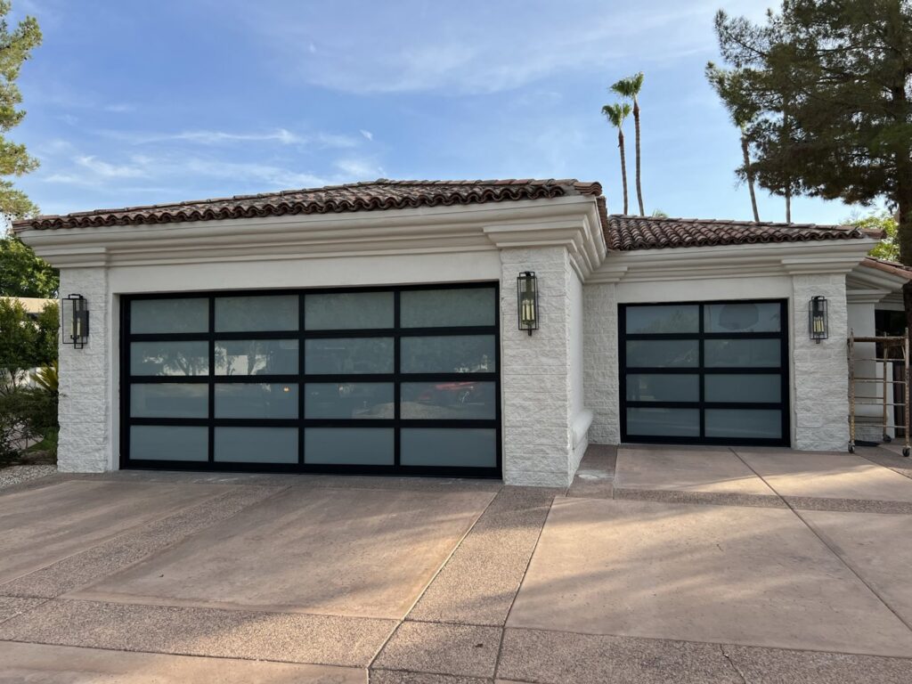 A modern house featuring two contemporary glass panel garage doors installed by Morning Star Garage Doors in Phoenix, AZ.