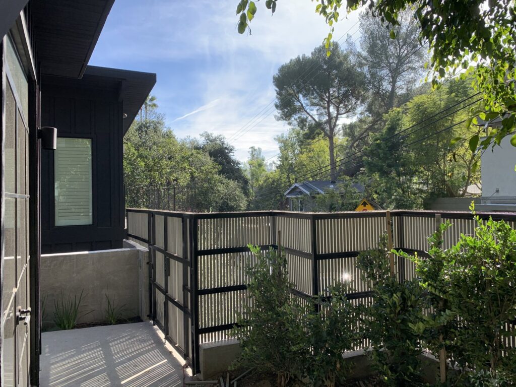 A contemporary metal and wood slat fence providing privacy and style, installed by Harwell Fencing & Gates Inc. in Los Angeles, CA.