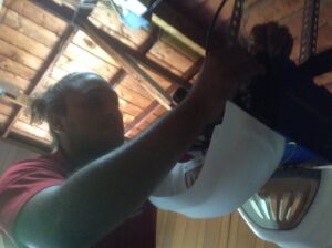 A contractor adjusting the light cover of a garage door opener during service by OklaHome Overhead Doors in Tulsa, OK