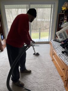 A carpet contractor from J&P United cleaning a residential carpet with professional equipment in Rochester, NY.