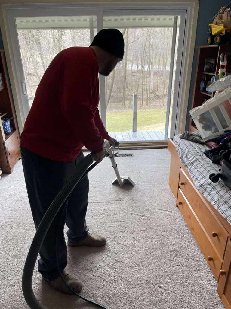 A carpet contractor from J&P United cleaning a residential carpet with professional equipment in Rochester, NY.