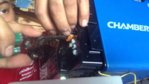 Close-up of a contractor's hands and tools working on the wiring of a Chamberlain garage door opener for OklaHome Overhead Doors in Tulsa, OK