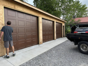 A contractor inspecting newly installed brown garage doors on a building under construction by Up Garage Door in Nashville, TN.