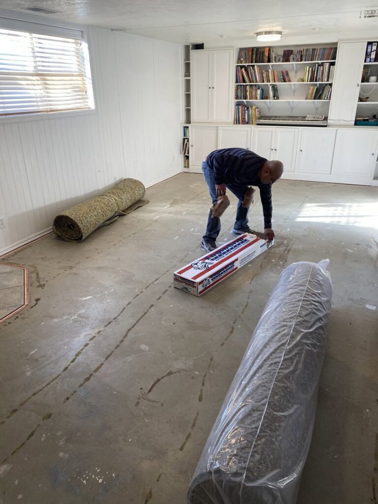 A contractor installing new carpet in a room for Taylor Carpets & Flooring in Provo, UT