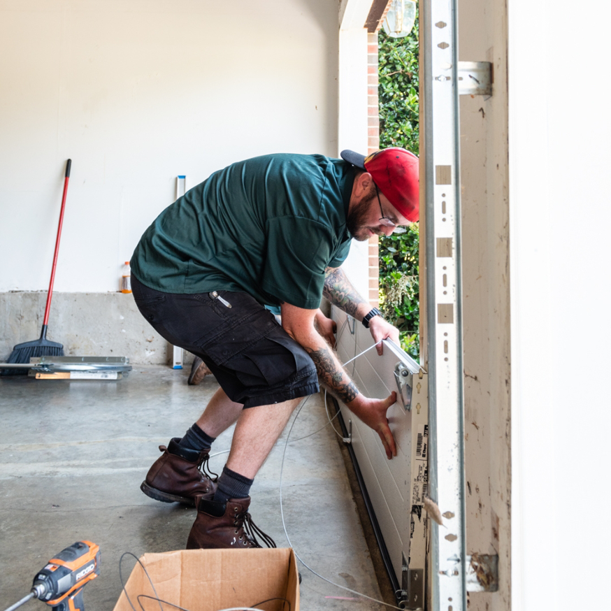 A garage door contractor installing hardware on a new garage door panel for Annapolis Garage Doors Inc. in Annapolis, MD.
