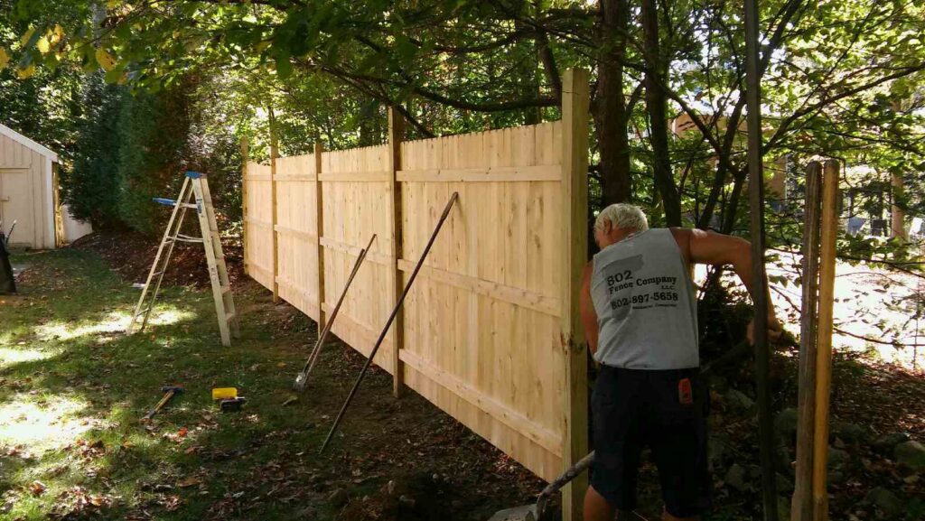 A contractor from 802 Fence Company LLC installing a wooden privacy fence in Shoreham, VT.