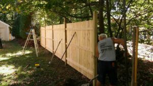 A contractor from 802 Fence Company LLC installing a wooden privacy fence in Shoreham, VT.