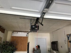 A contractor pulling the emergency release cord on a white sectional garage door opener during service by OklaHome Overhead Doors in Tulsa, OK