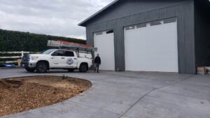 A Discount Garage Door Company truck at a job site with new white garage doors in Spokane, WA.