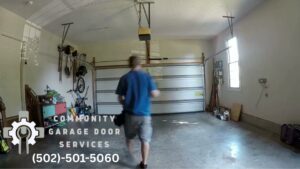 A contractor walking inside a garage after working on a white garage door, showcasing services by Community Garage Door Services in Louisville, KY.