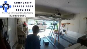 A contractor working on a garage door inside a residential garage, with the company truck visible outside, by Community Garage Door Services in Louisville, KY.