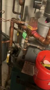 Close-up view of copper pipes and valves, part of a heating or plumbing system, serviced by Markool Heating Cooling Plumbing in Frederick, MD.