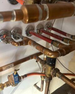 Close-up of copper piping and valves, part of a heating or plumbing system serviced by Jump HVAC in Lakewood, CO.