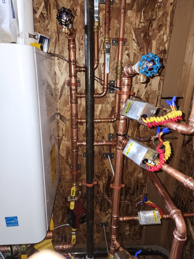 Detailed view of copper piping and valves connected to a tankless water heater by D & D Heating & Air in Brighton, CO.