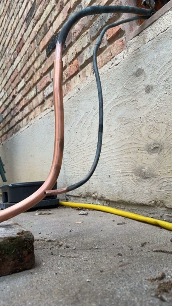 Close-up of copper refrigerant lines and insulated pipes for an HVAC system installed by Texas Air & Heat in Arlington, TX.