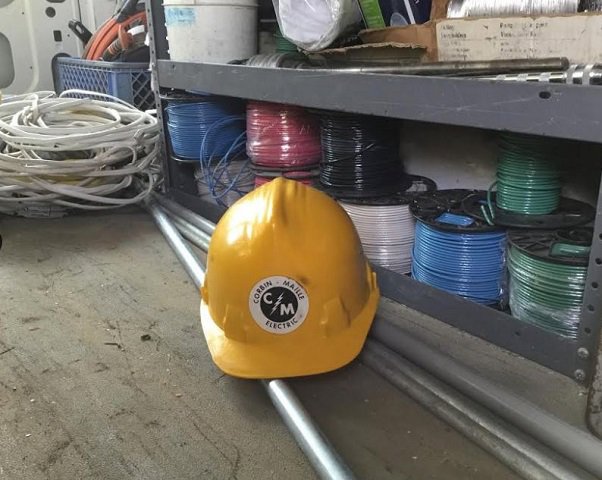 A Corbin & Maille, Inc electrician's hard hat and spools of electrical wire inside a service van in Erie, PA.
