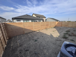 A corner section of a new horizontal slat wooden fence enclosing a backyard by Nailed It Fencing in Williston, ND.