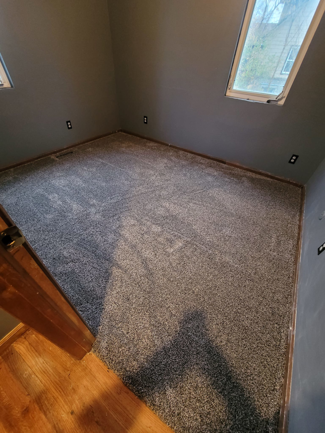 A corner room featuring new grey carpet flooring installed by Washington Family Flooring LLC in Bellevue, NE.