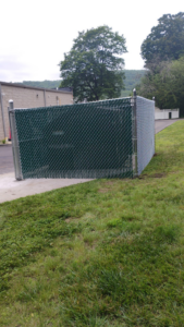 A corner section of green chain-link fence with privacy slats installed by Oxford Fence Company in Oxford, CT.