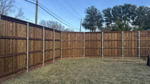 A corner section of a stained wood fence with robust metal posts by Franco Fence in Garland, TX.