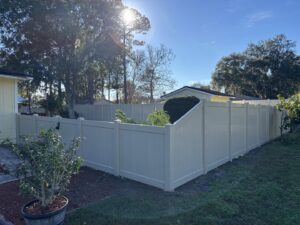 A tan vinyl privacy fence expertly installed around a corner of a property by Masters Fence Contracting in Jacksonville, FL.