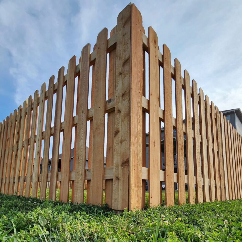 A low-angle view of a sturdy corner of a wood picket fence by Hotshot Fencing and Gates in Kansas City, MO.