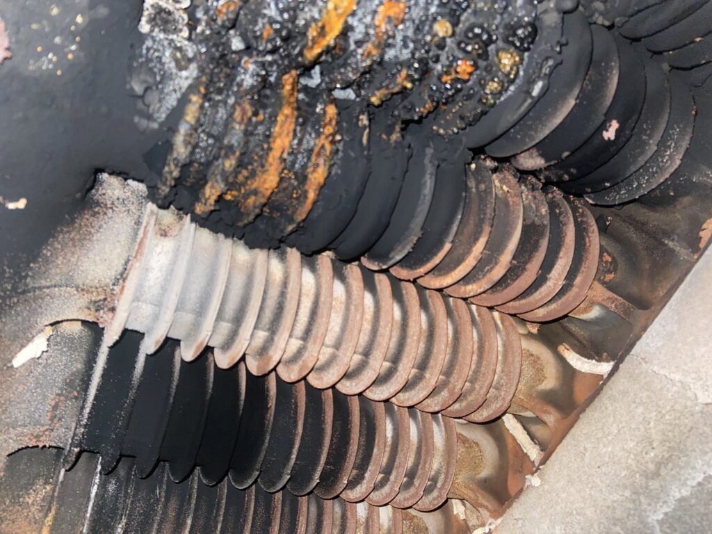 A close-up view of a severely corroded and burnt furnace heat exchanger, indicating a repair need for Around The Town Heating and Cooling in Chicago, IL.