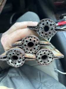 A technician holding severely corroded furnace heat exchangers, indicating a need for repair from Fine Line HVAC LLC in Isanti, MN.