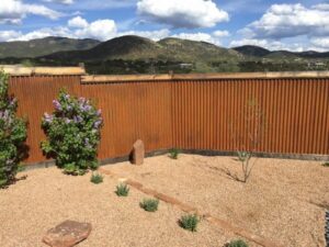 A corrugated metal backyard fence with a rustic finish and mountain views by Fence Company Tucson in Tucson, AZ.