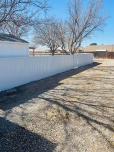 A white corrugated metal fence under construction, showing posts and panels by Pecos Construction and Fencing, LLC in Roswell, NM.