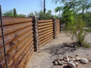 A unique corrugated metal fence with decorative stone-filled posts by Fence Company Tucson in Tucson, AZ.