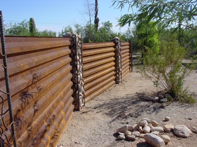 A unique corrugated metal fence with decorative stone-filled posts by Fence Company Tucson in Tucson, AZ.