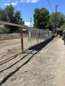 A corrugated metal fence under construction with wooden posts by Tomahawk Fencing in Riverton, WY.