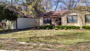 A modern corrugated metal privacy fence installed next to a residential home by Pro Insulation and Fence in Wichita Falls, TX.