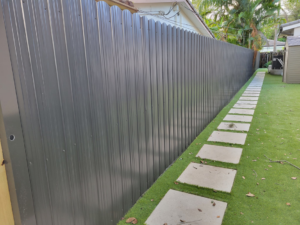 A newly installed dark gray corrugated metal privacy fence in a backyard by Southeastern Fence Corp. in Pembroke Pines, FL.