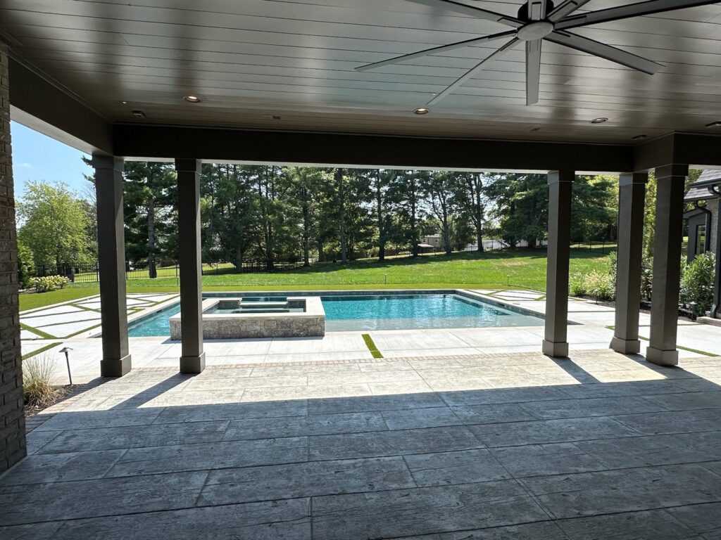 A view of a rectangular swimming pool and spa from a covered patio by Top Tier Pools in Franklin, TN.