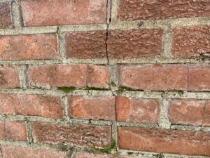 Close-up of cracked and moss-covered brick masonry, indicating chimney or fireplace repair work by Indy Ignited in Indianapolis, IN.