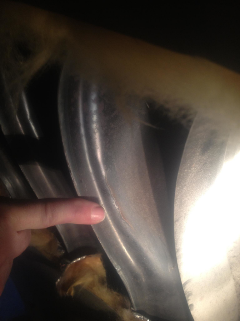 A finger pointing to a crack on a heat exchanger during a furnace inspection by Geddes Heating and Cooling in Aurora, CO.